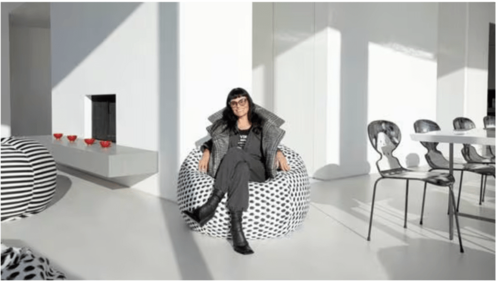 Norma Kamali wearing gray and black sitting on a black and white polka dot bean bag
