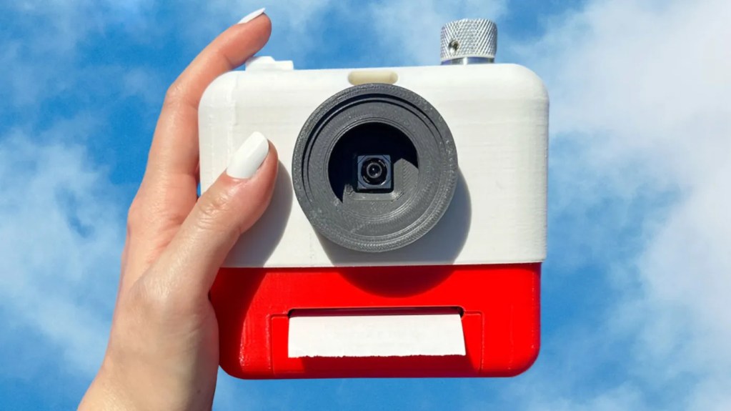 Person holding a white and red camera on a sky blue background