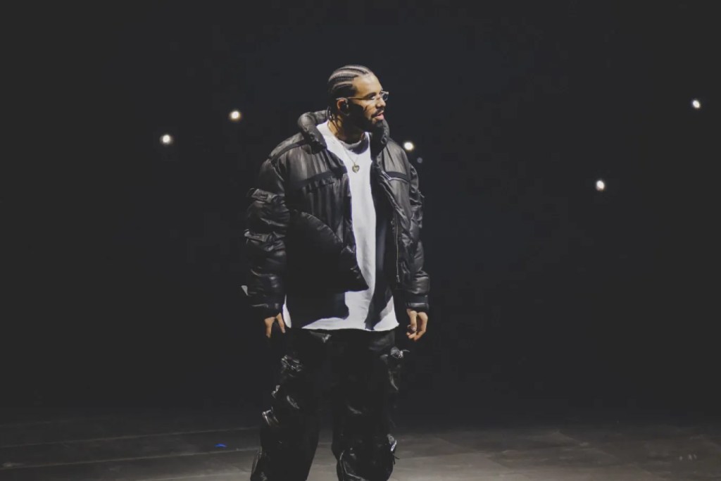 Musician in a black puffer coat on a dark stage backlit