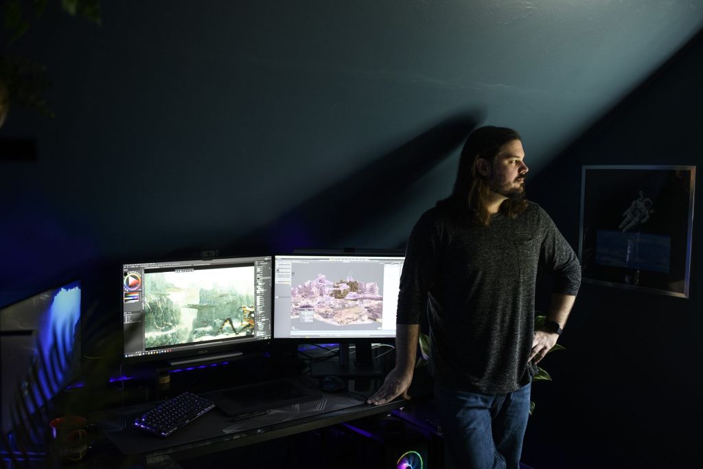Man in front of a dark background and multiple computer screens