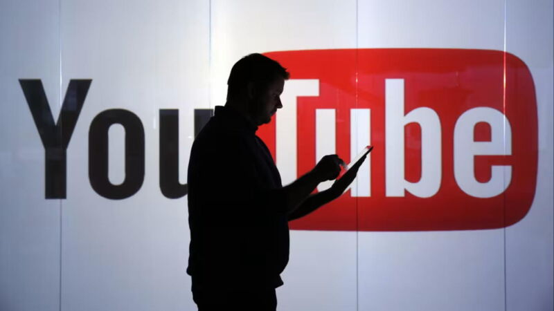 A person in silhouette walking in front of a YouTube sign
